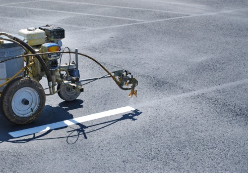 machine spraying paint on newly laid asphalt